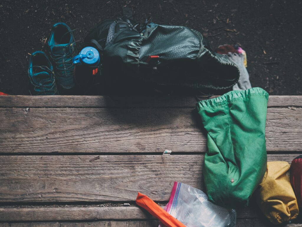 A pair of hiking boots and a layered outfit laid out for a camping trip.