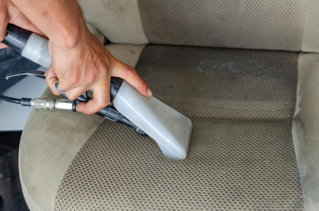 Handheld car vacuum cleaner in use on car seat