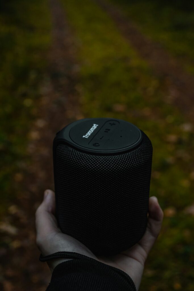 Compact Bluetooth speaker playing music outdoors on a picnic table